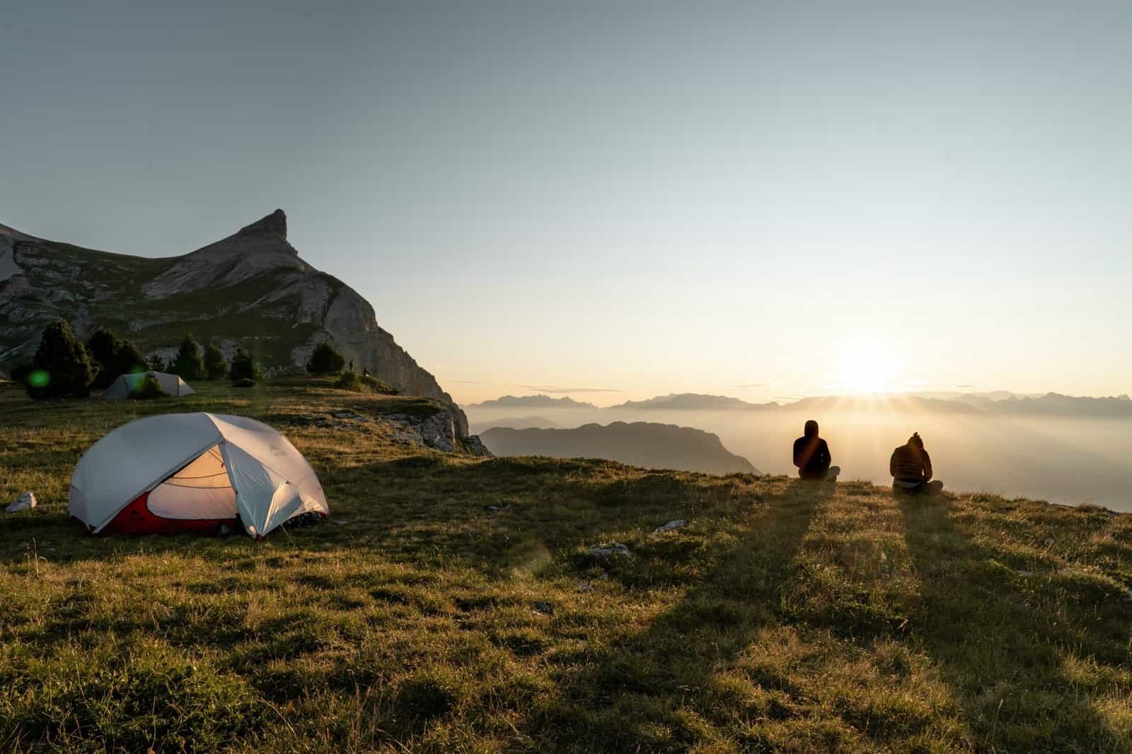 Solo hikers and a 2-person tent in a scenic mountain location