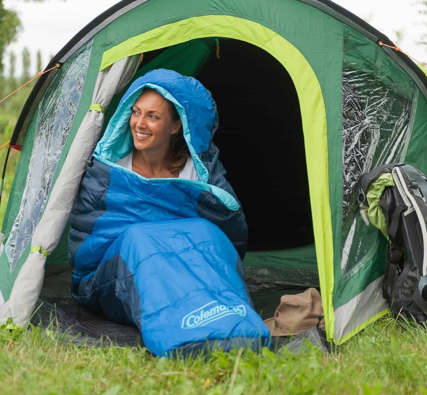 a woman is in a mummy sleeping bag and sitting in the tent