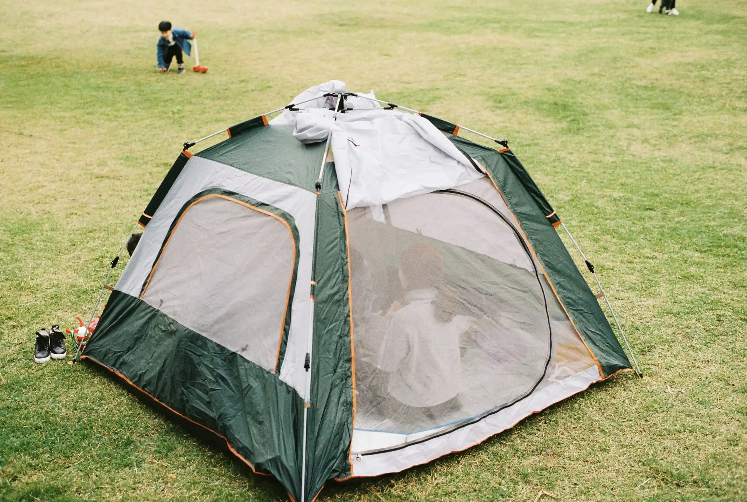 Camping tent set up on grassy field for outdoor adventure.