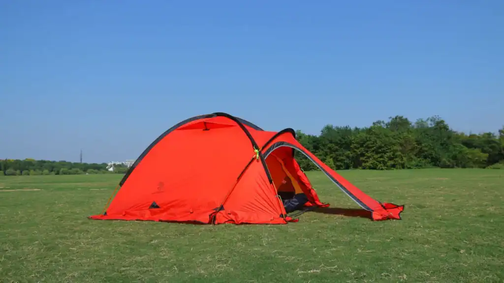 Red camping tent in open field.
