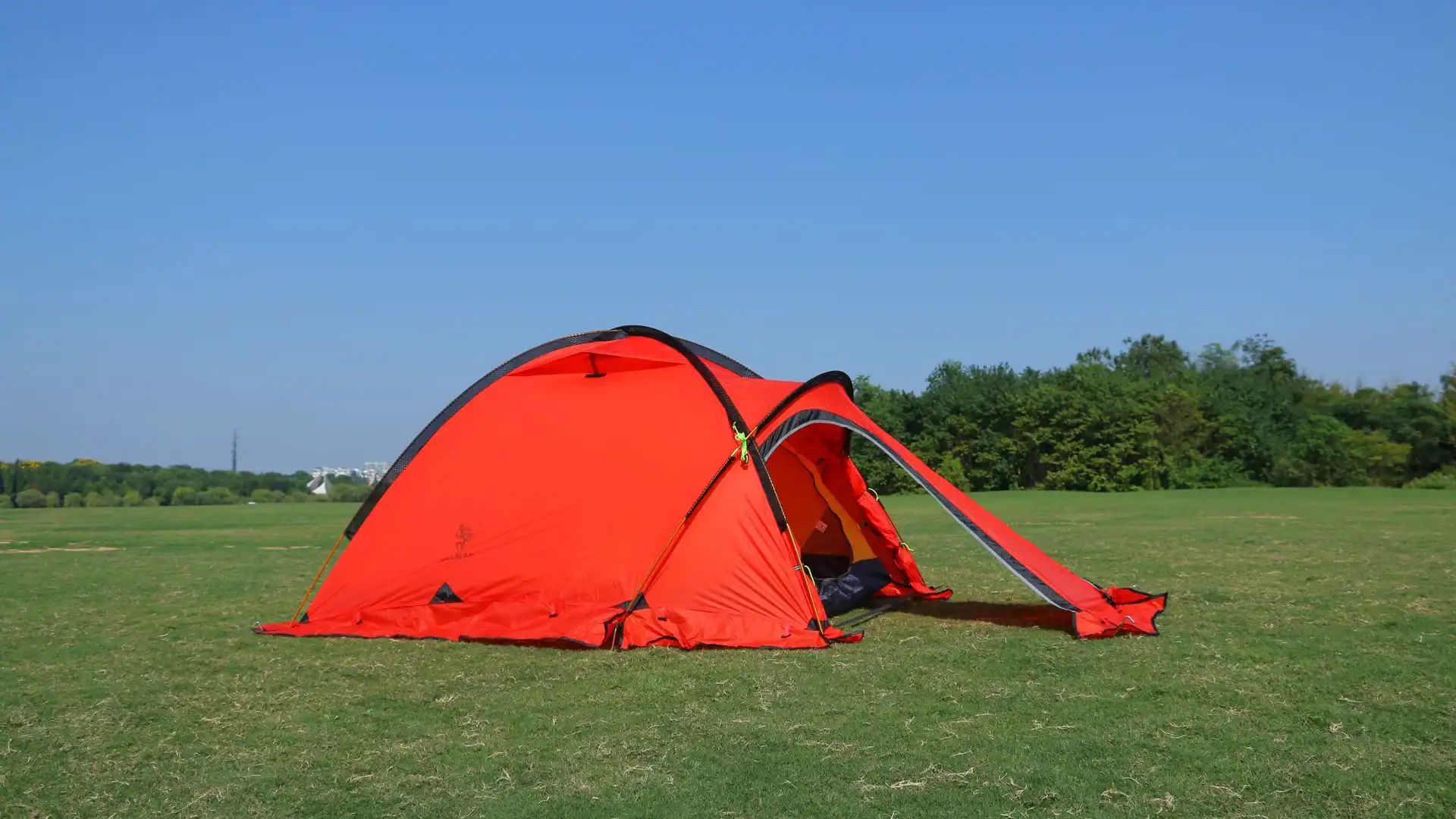 Red camping tent in open field.