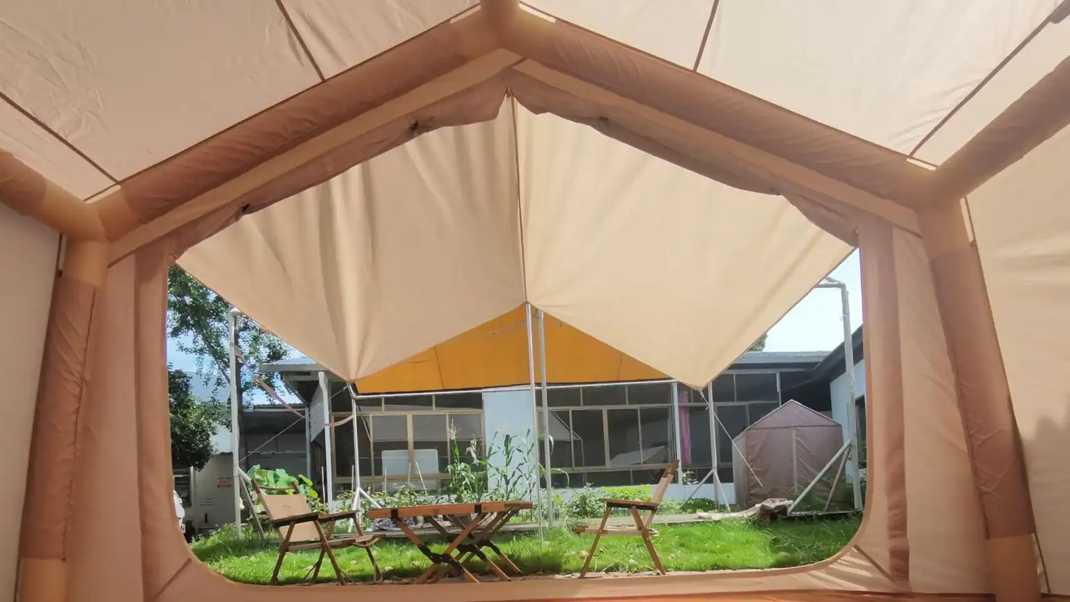 Barraca de camping ao ar livre com móveis de jardim e vegetação.