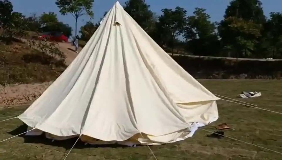 Canvas tent set up on grassy field with trees in the background at Kelyland Outdoors.