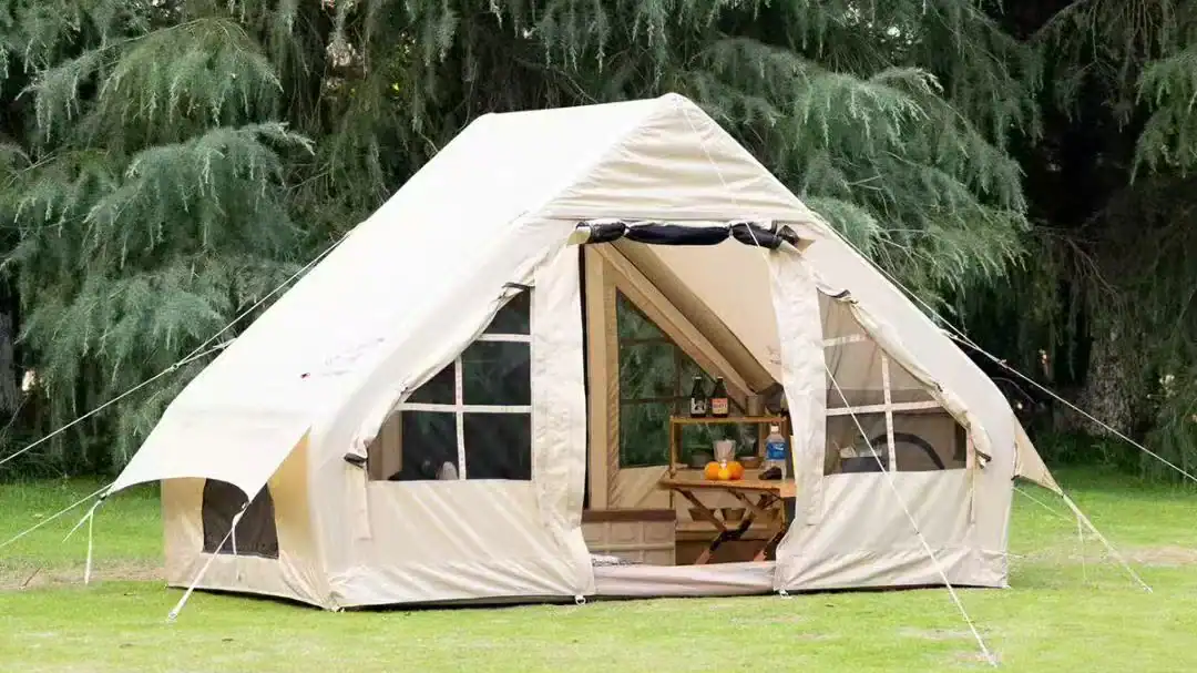 Large beige canvas glamping tent set up outdoors in a lush green forest.