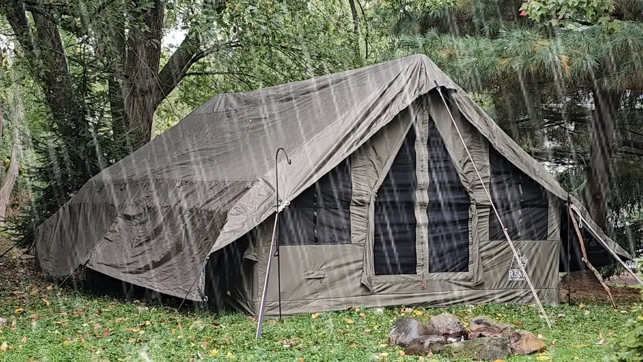 Grande barraca de camping ao ar livre em um ambiente florestal com proteção contra chuva.