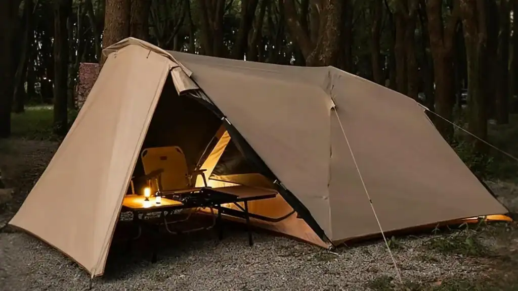 Camping tent with interior lighting set up in a wooded area at night.