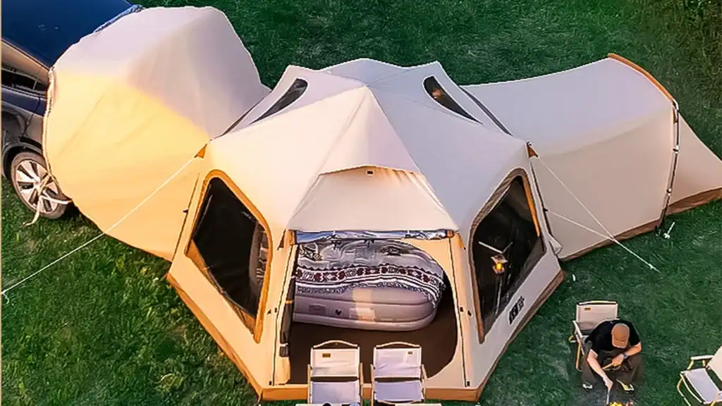 A spacious family camping tent set up in a grassy outdoor area, featuring comfortable outdoor furniture and a cozy interior view.