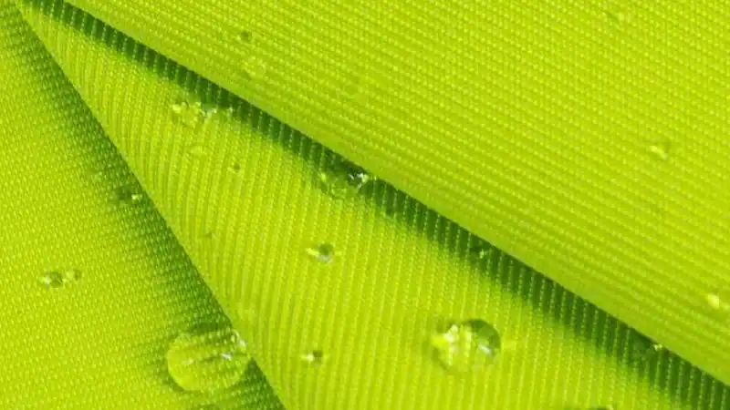 Close-up of bright green outdoor fabric with water droplets.