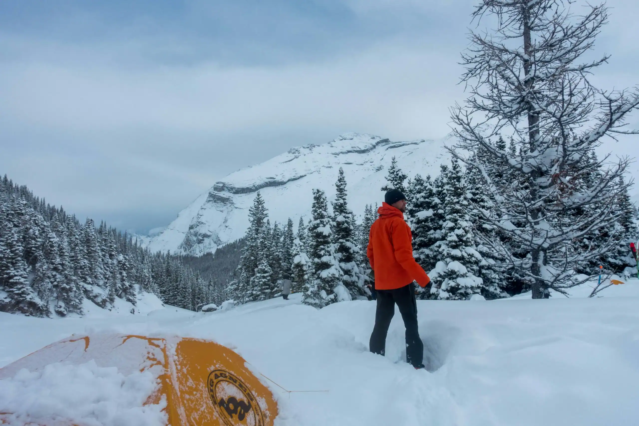 Person in red jacket snowshoeing in a snowy mountain landscape.