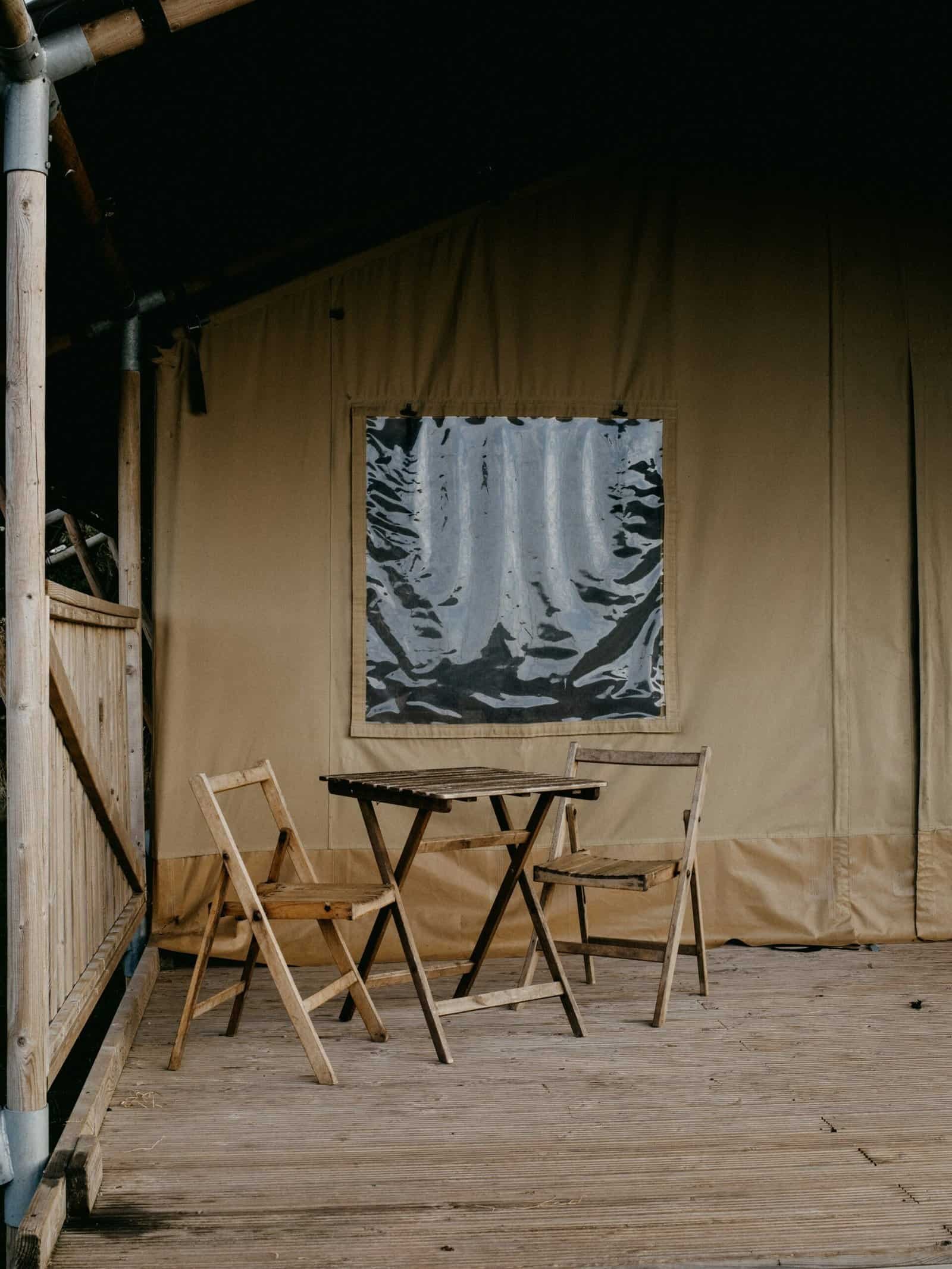 Outdoor seating with wooden table and chairs under a tent at Kelyland Outdoors.