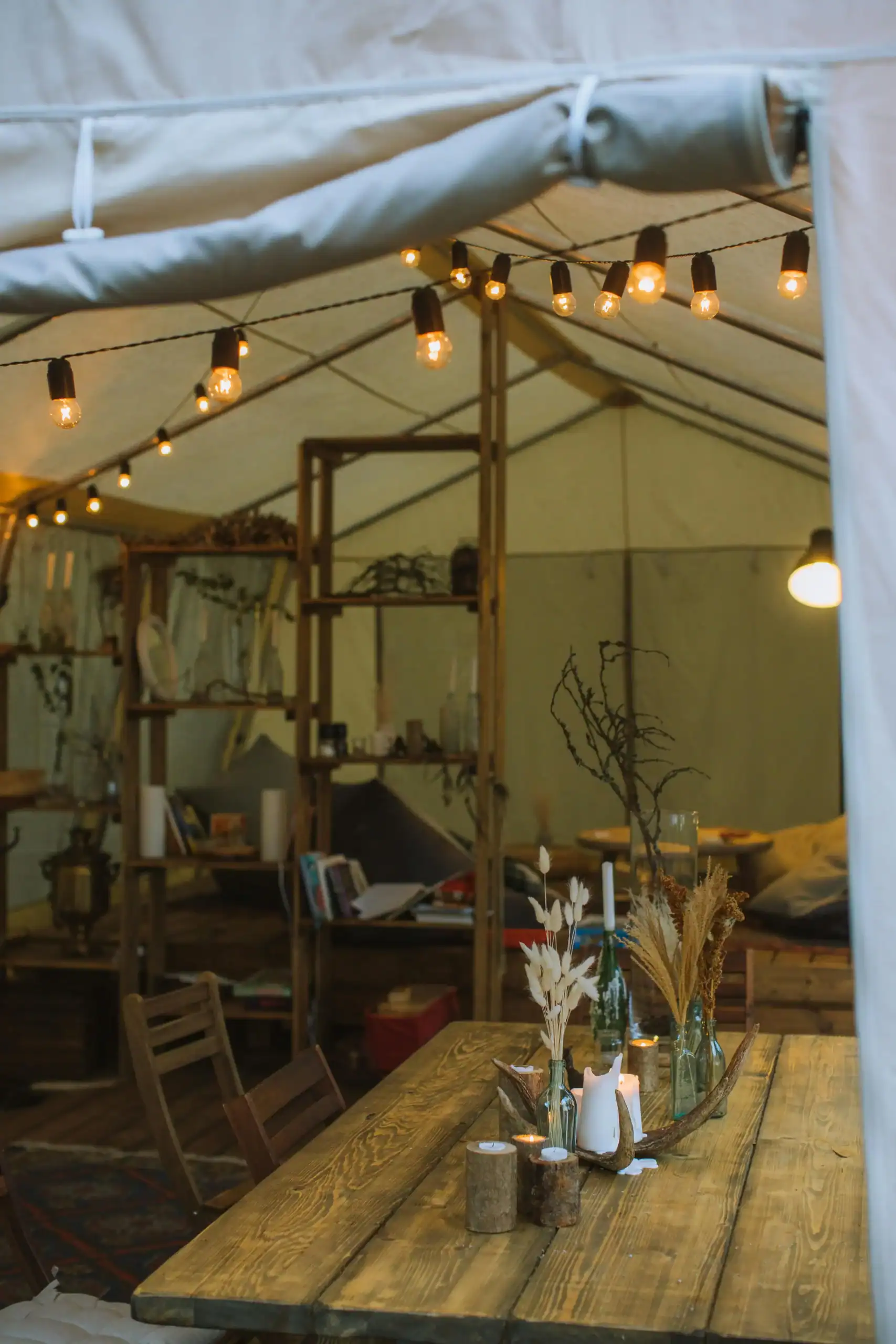 Tenda ao ar livre decorada com cordões de luzes quentes e móveis rústicos.