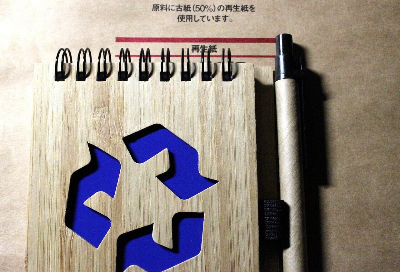 Case Study: Launching a Recycled PET Camping Tent Line for European Market 1 Cuaderno de papel reciclado con un bolígrafo y un símbolo de reciclaje azul, promoviendo la sostenibilidad y la conciencia ecológica.