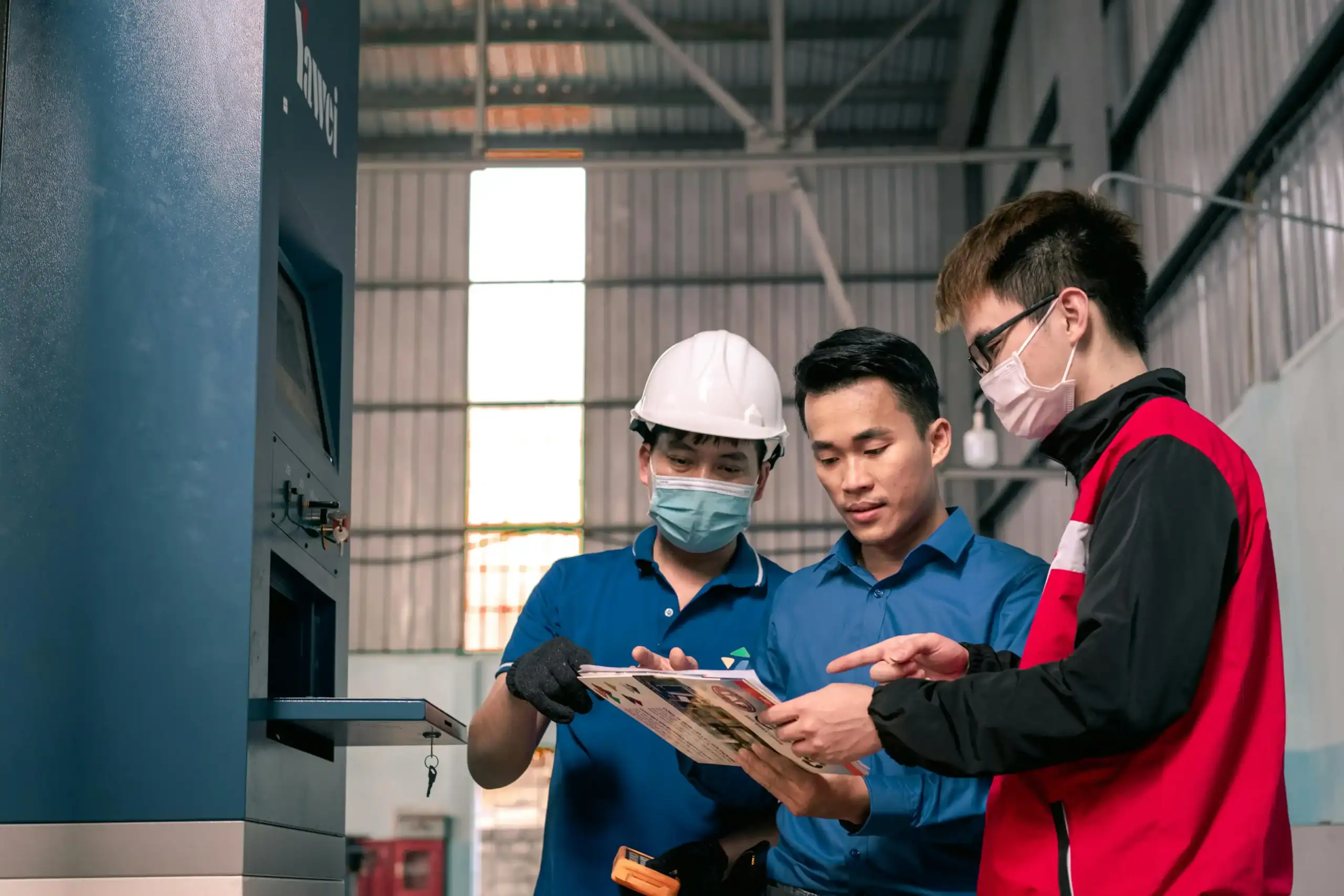 China Outdoor Factory Vetting Checklist: Avoid $15k Losses 2 Industriearbeiter überprüfen Gerätehandbuch in einer Fabrikumgebung.