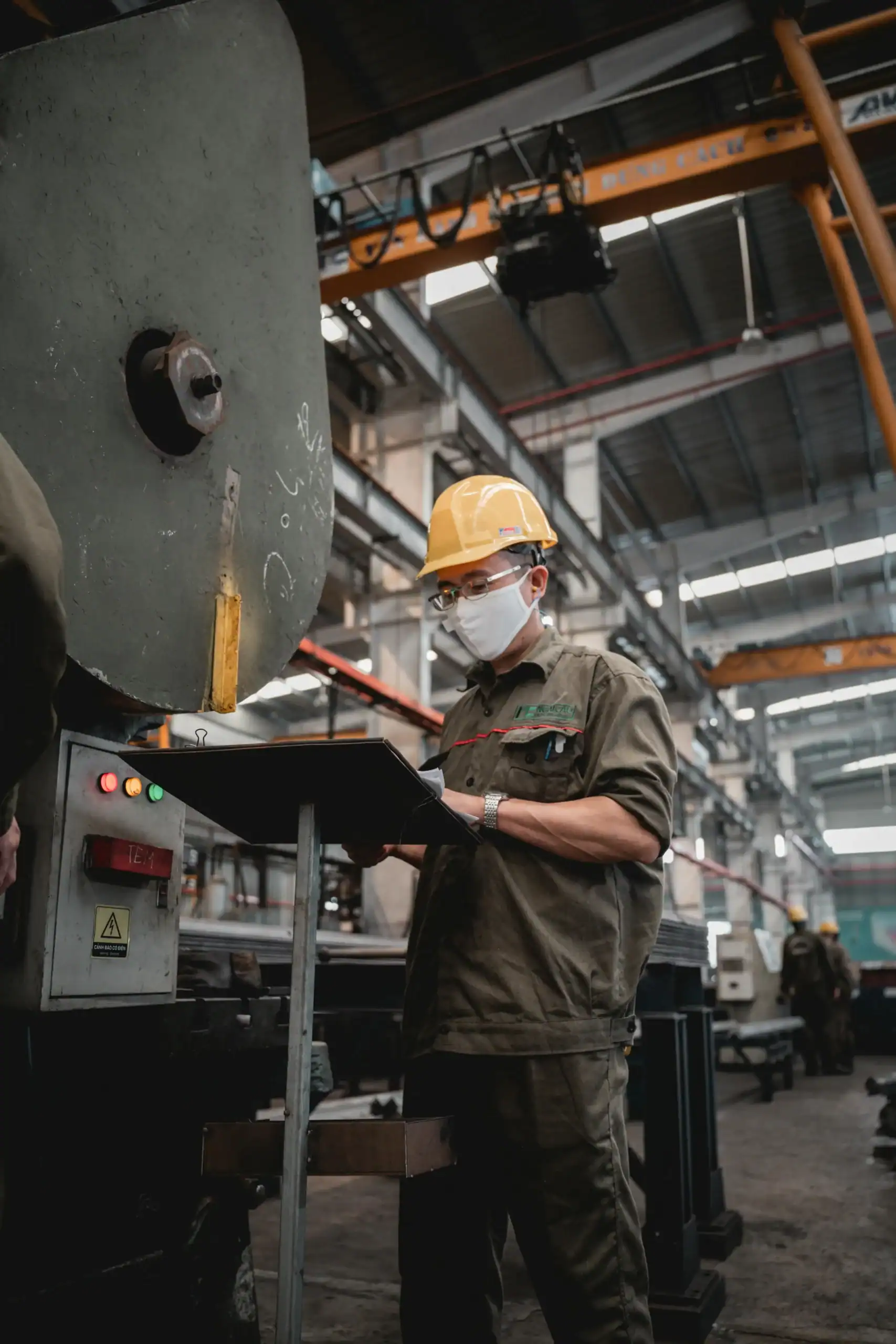 China Outdoor Factory Vetting Checklist: Avoid $15k Losses 3 Factory worker wearing safety gear inspecting machinery in industrial plant.