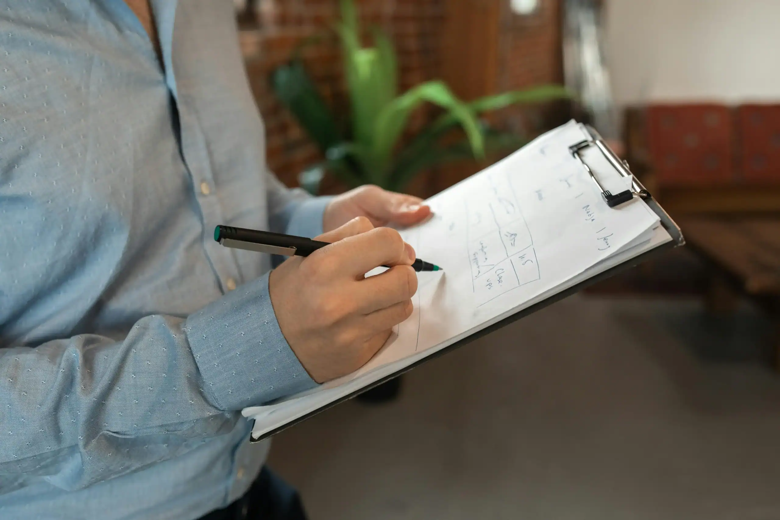 China Outdoor Factory Vetting Checklist: Avoid $15k Losses 6 Person writing on a clipboard in a cozy indoor setting.