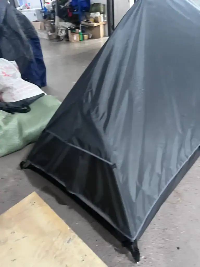 Importing from China: Step Guide 1 Black outdoor tent displayed in a factory environment with visible equipment and materials in the background.