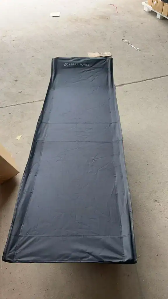 Camping Cot Safety Standards: Avoid $50k Compliance Failures 2 Portable lightweight camping cot with 'Terra Force' branding displayed on a concrete outdoor surface, boxes visible nearby.