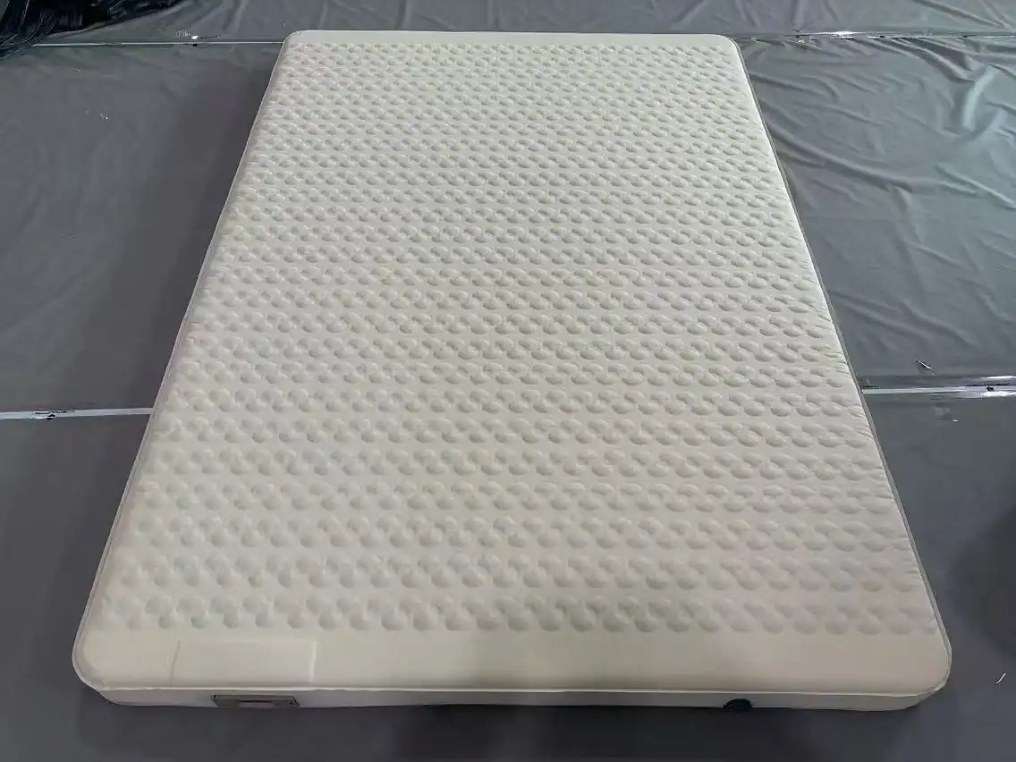 White foam mattress with textured surface on black plastic background.