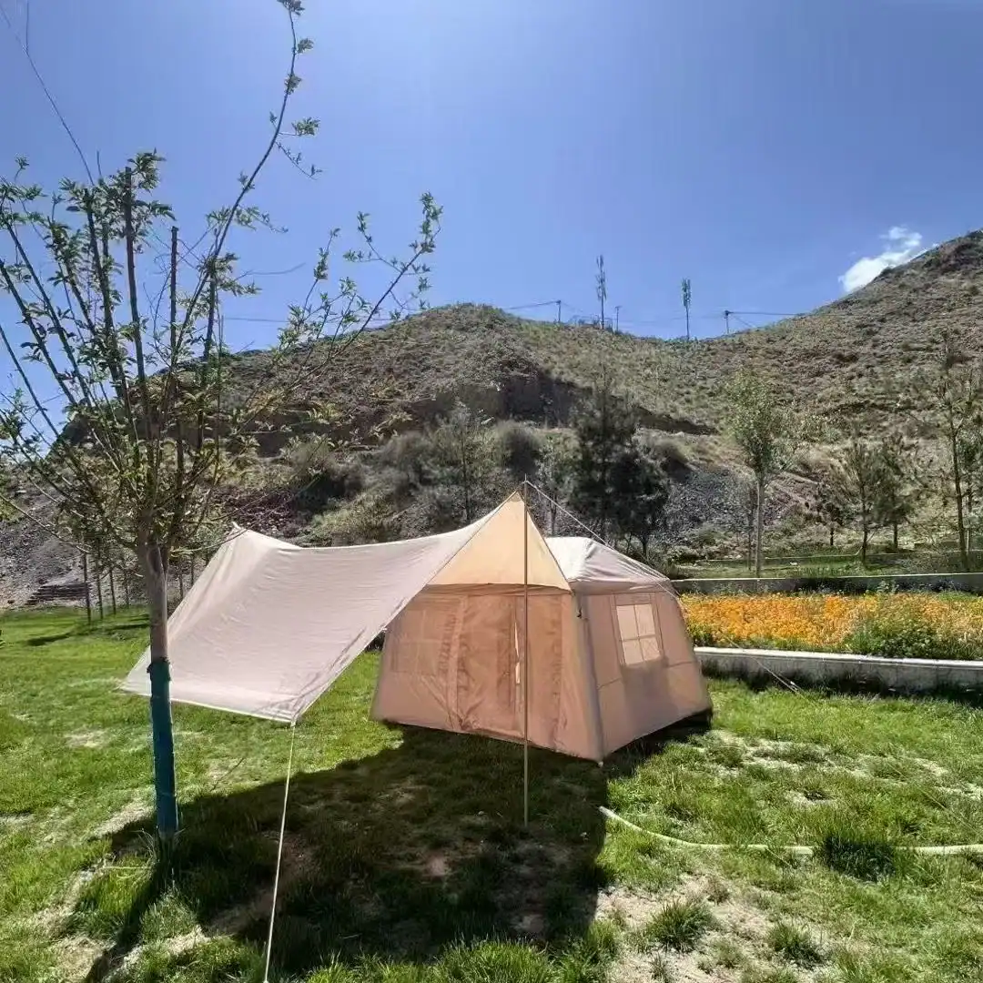 Carpa de campamento instalada al aire libre con montañas y árboles de fondo.