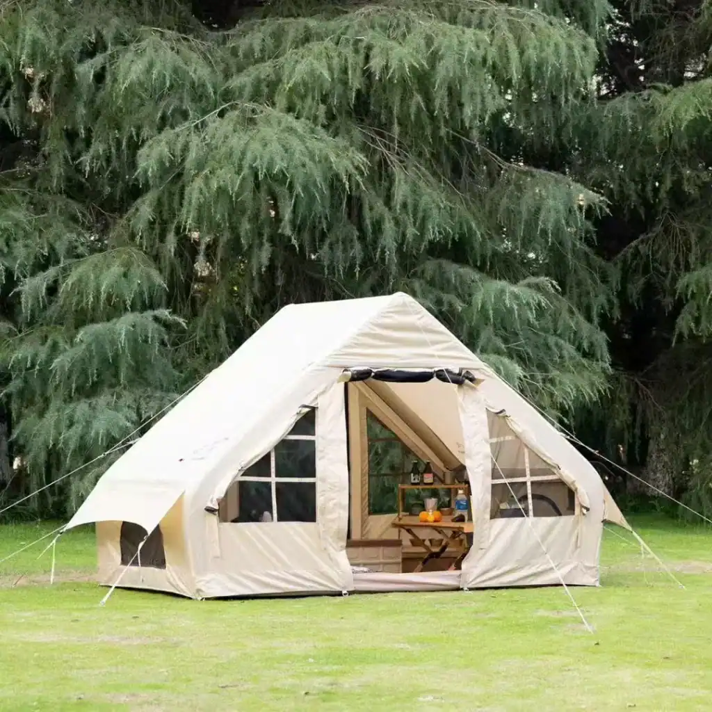 Canvas tent set up outdoors in a grassy area with trees in the background.