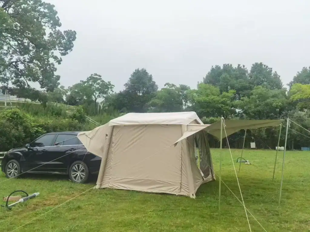 Inflatable Tent Defects: 7 to Catch Before Shipment 6 Large beige camping tent with attached canopy in a grassy outdoor setting.