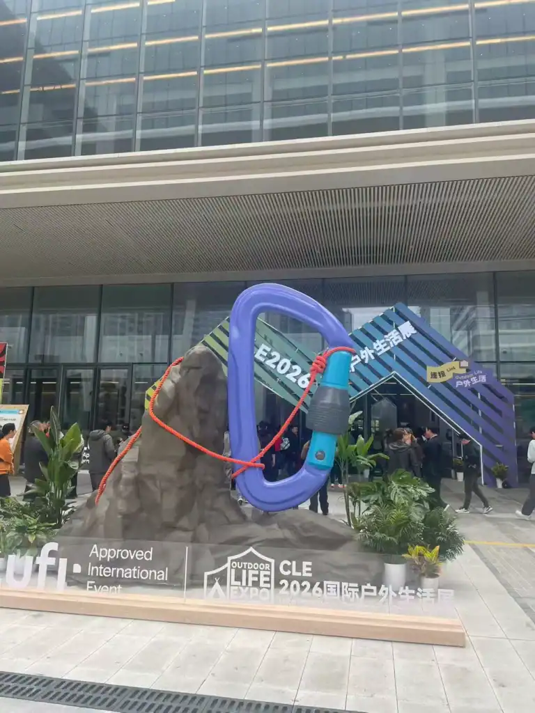 Large outdoor sculpture at CLE 2026 Expo with a giant rock and blue carabiner.