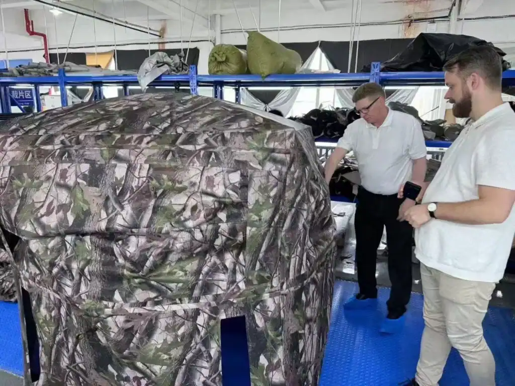Air Tent vs Pole Tent: 5 Failure Modes B2B Buyers Must Know 5 Two men examine a camouflage tent in a warehouse setting.