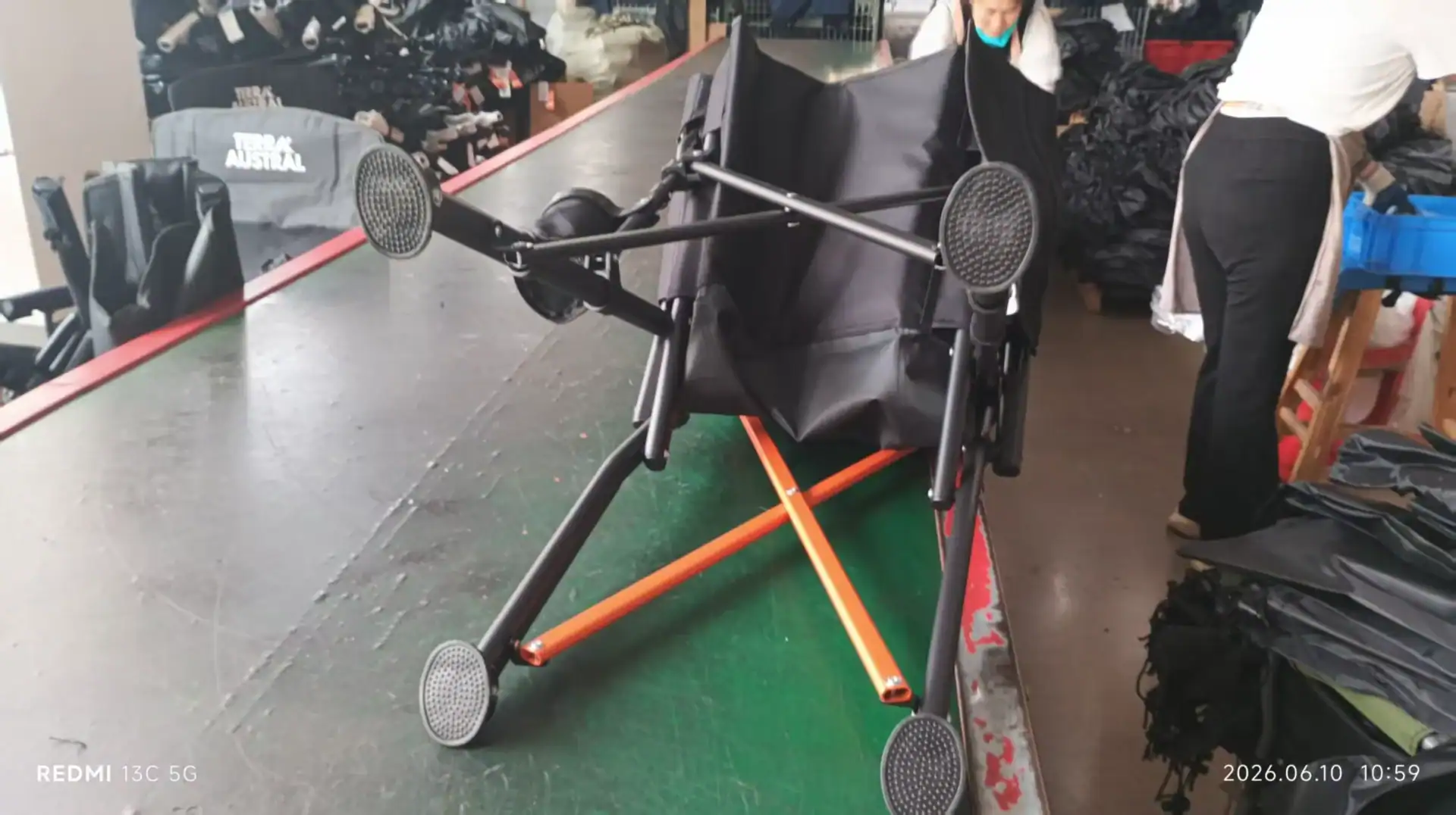 Folding Wagon Wheel Types: PVC, PU, EVA, TPE for OEM 2 Folded black and orange stroller on a green surface at Kelyland Outdoors.