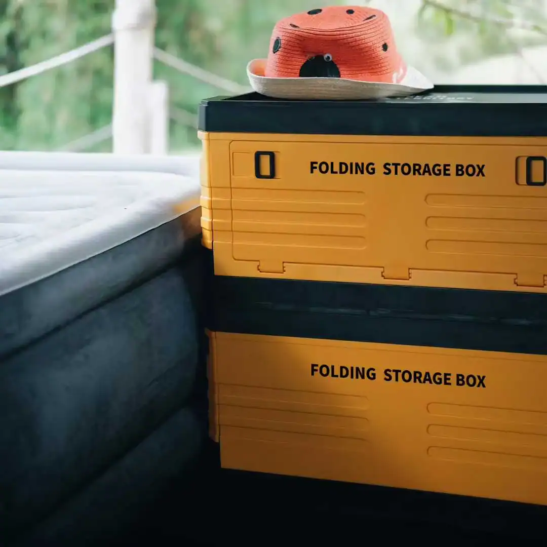Yellow folding storage boxes with a hat on top, outdoors setting.
