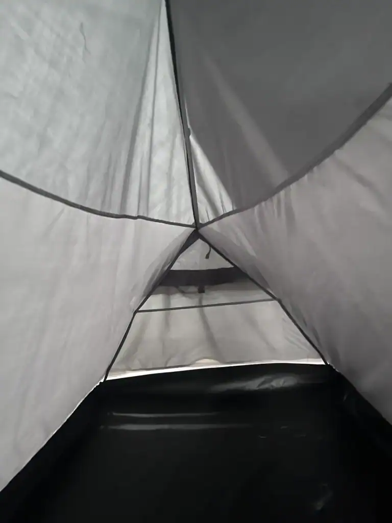 Inside view of a gray tent showing its fabric walls, floor, and mesh vent for ventilation. Ideal for camping gear context.