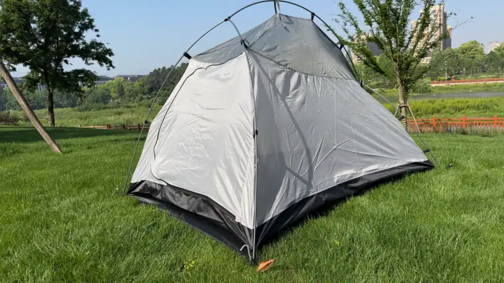 Rahmenversagen bei Glamping-Zelten: 5 Wege, wie Stahl Sie Geld kostet 2 Silbernes und schwarzes Campingzelt auf einer grünen Grasfläche mit Bäumen und einer ruhigen Außenparkumgebung.