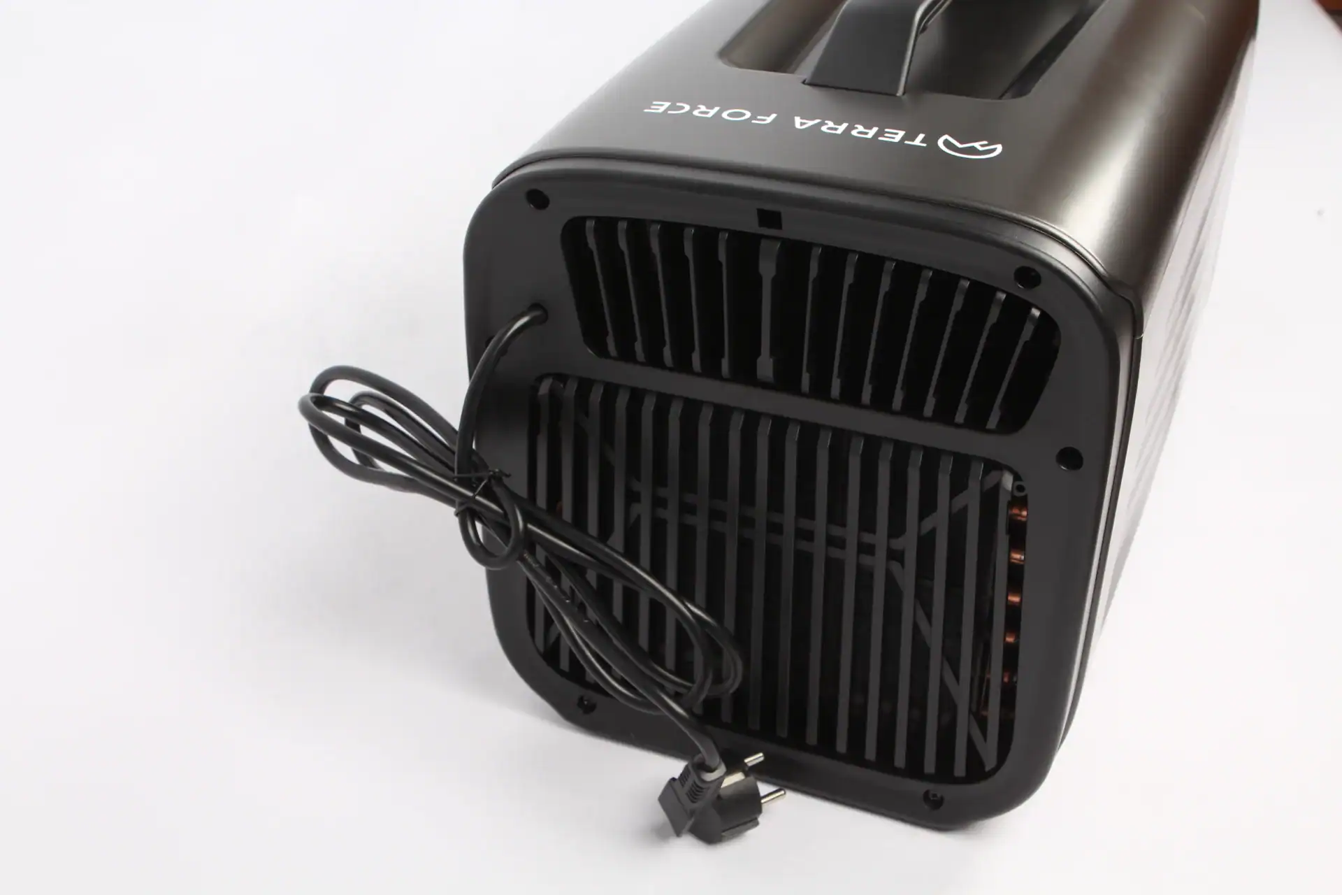 The back view of a portable air cooler with ventilation grills and a neatly coiled power cord on a white background.
