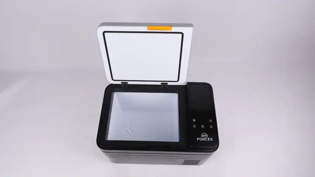 Top view of a portable black-and-white camping refrigerator with an open lid, touch controls, and compact design for outdoor use.