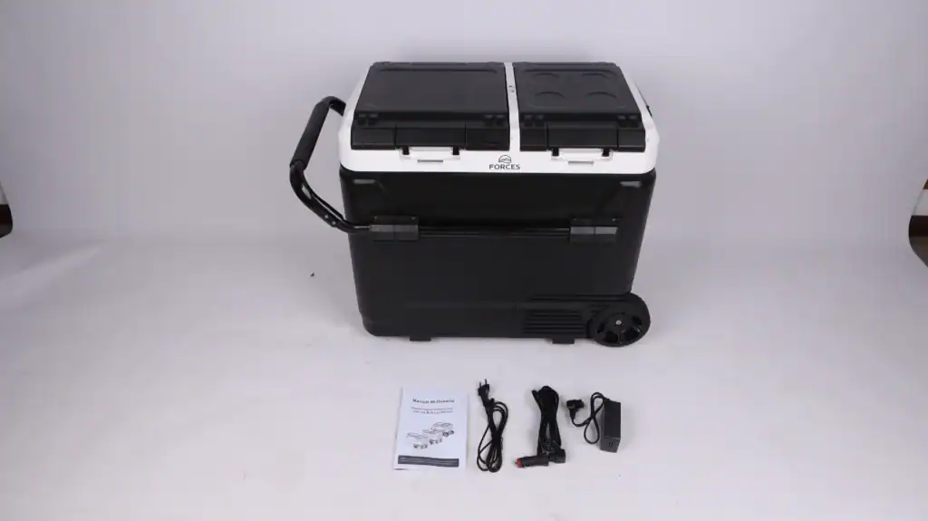 Glacière électrique portable noire et blanche avec poignée attachée, deux compartiments séparés, roues, câbles d'alimentation inclus et manuel d'utilisation sur fond blanc.