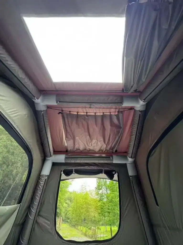 Interior of a camper van with a skylight and window view of nature.