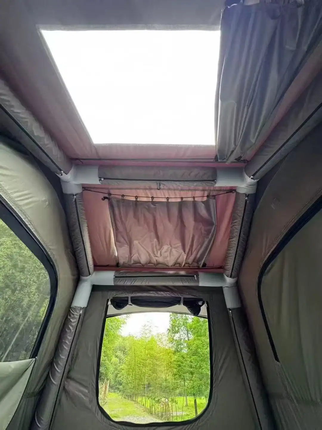 Interior de uma van camper com claraboia e vista pela janela para a natureza.