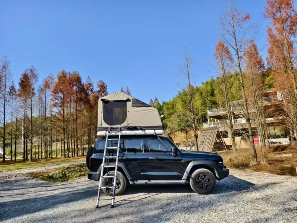 PVC Fabric for Inflatable Tents: 3 Critical Specs 1 Black SUV with rooftop tent parked in a forested outdoor area.