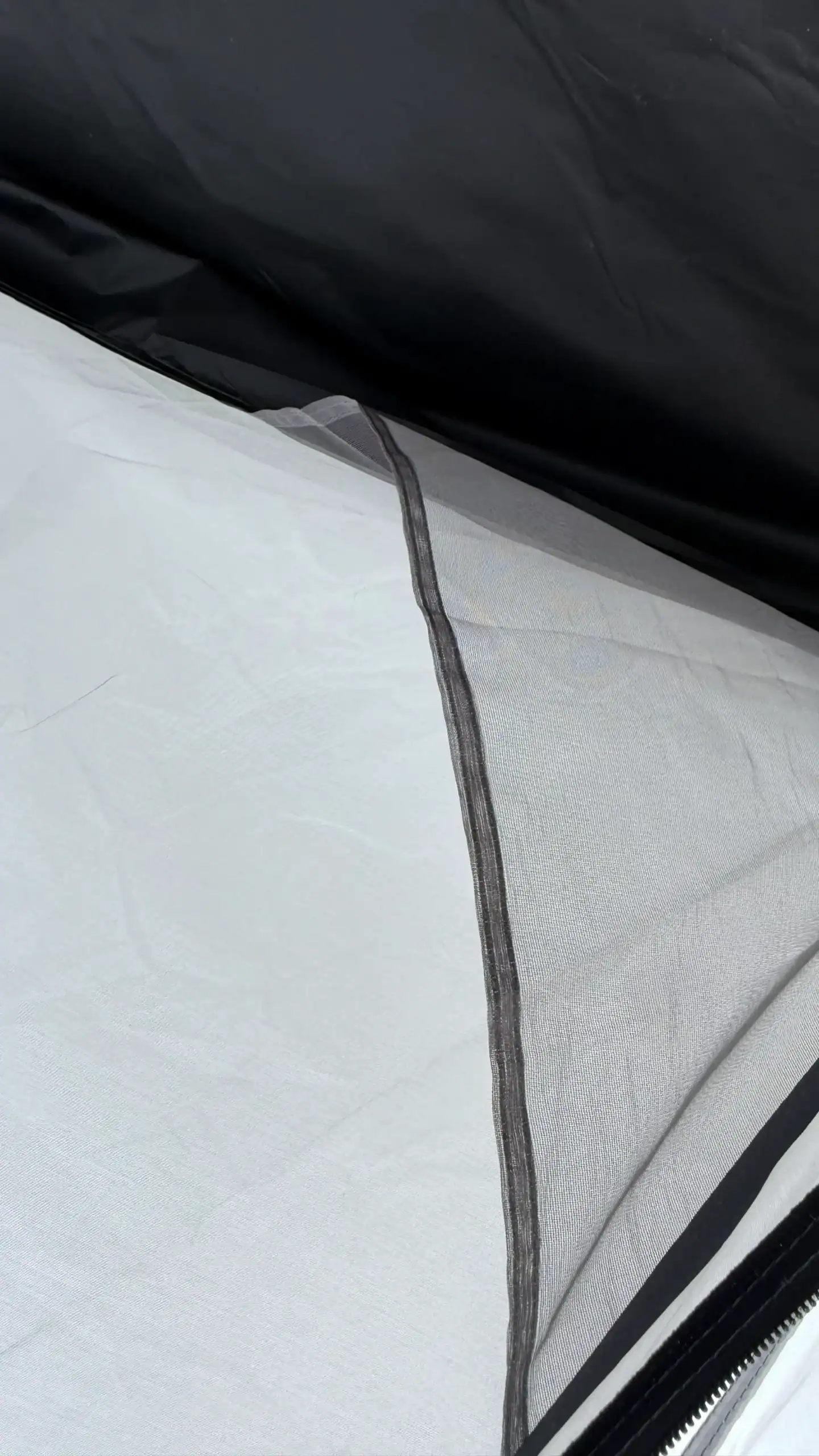 Inflatable Tent Cleaning: 7 Steps to Save PU Coatings 18 Close-up view of camping tent fabric showing black outer layer, white inner material, and a mesh seam for ventilation.