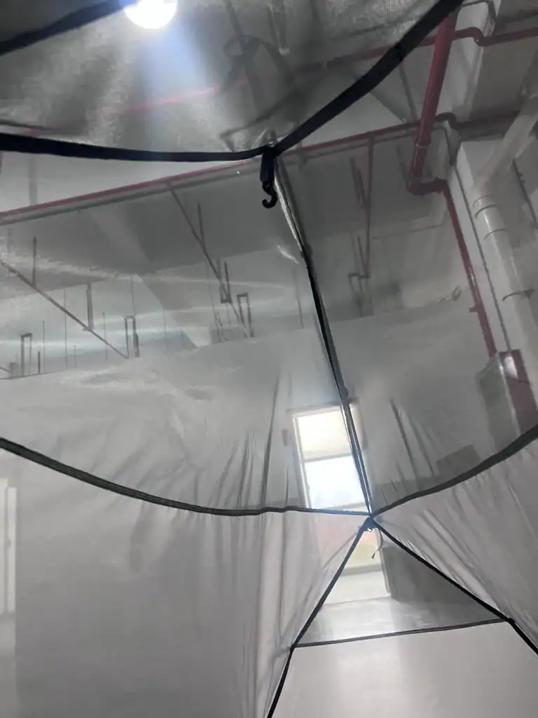 Importing from China: Step Guide 4 Close-up view of the inside of a tent showcasing fabric stitching, mesh panels, and a hook under factory lighting with visible ceiling pipes.