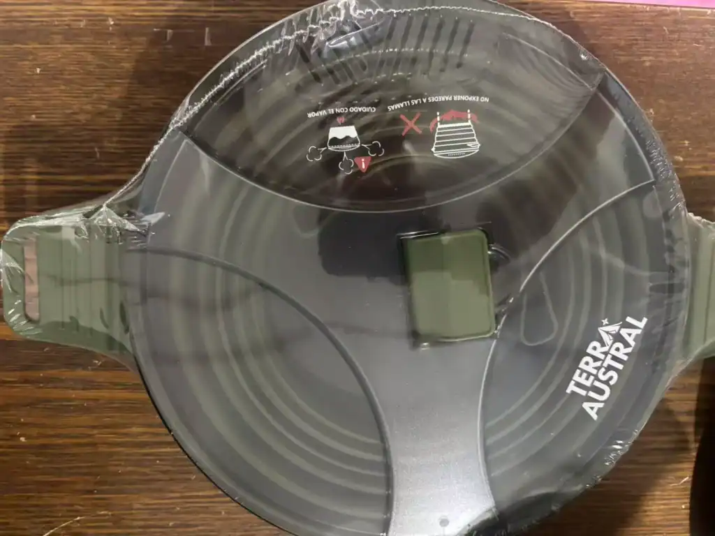 Foldable camping cooking pot by Terra Austral with a compact design and sealed packaging, placed on a wooden surface.