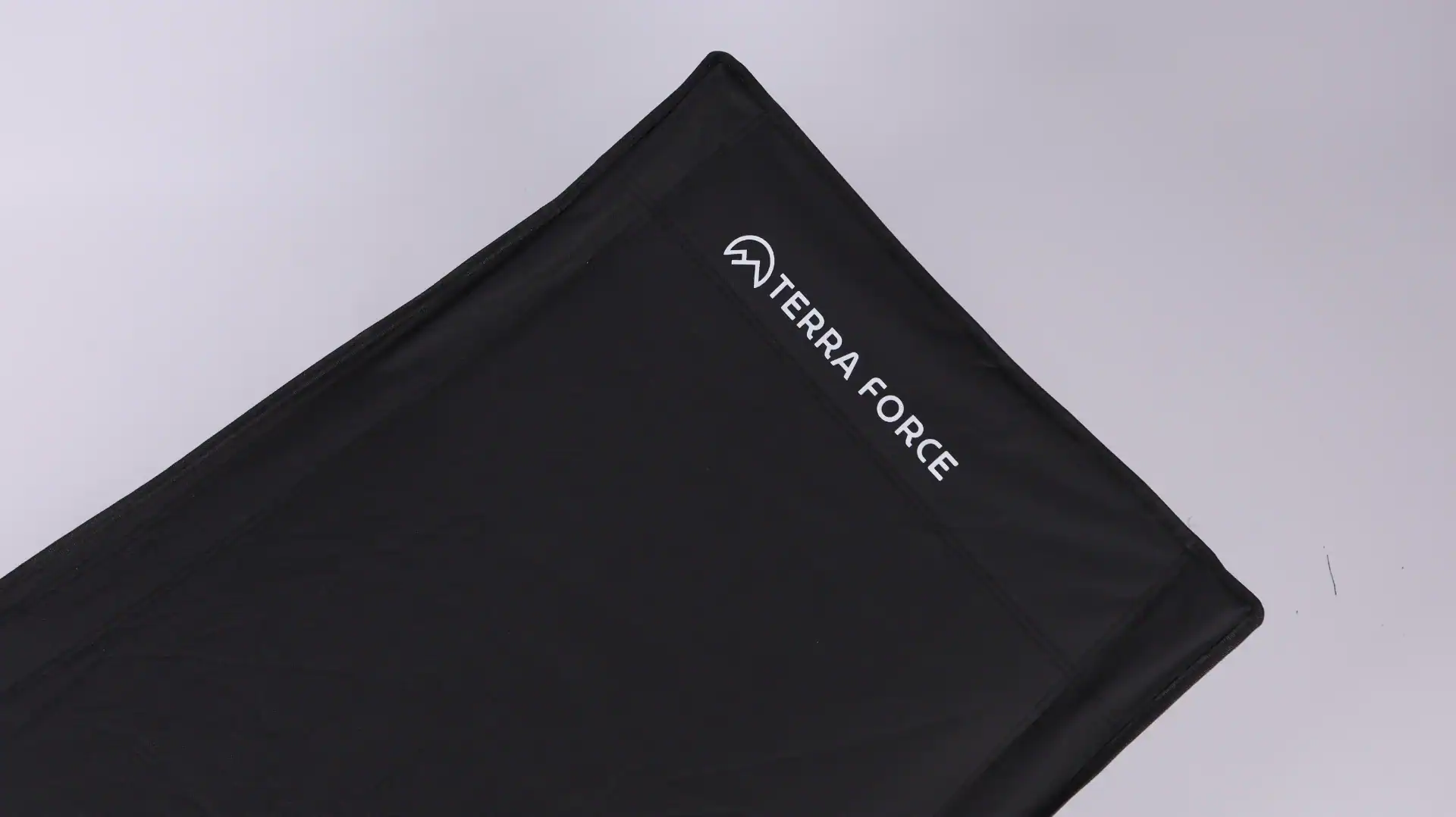 PVC vs PU Coated Wagon Fabric: Waterproof & UV Lab Test Data 15 Close-up of black fabric with 'Terra Force' logo, part of an outdoor chair design.