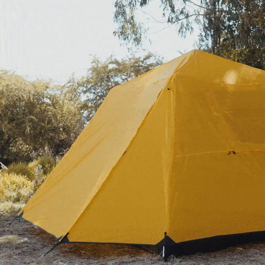 Custom Glamping Tent Printing: Artwork, Pantone & Logo Guide 4 A bright yellow camping tent set up outdoors in a wooded area with sunlight filtering through the trees.