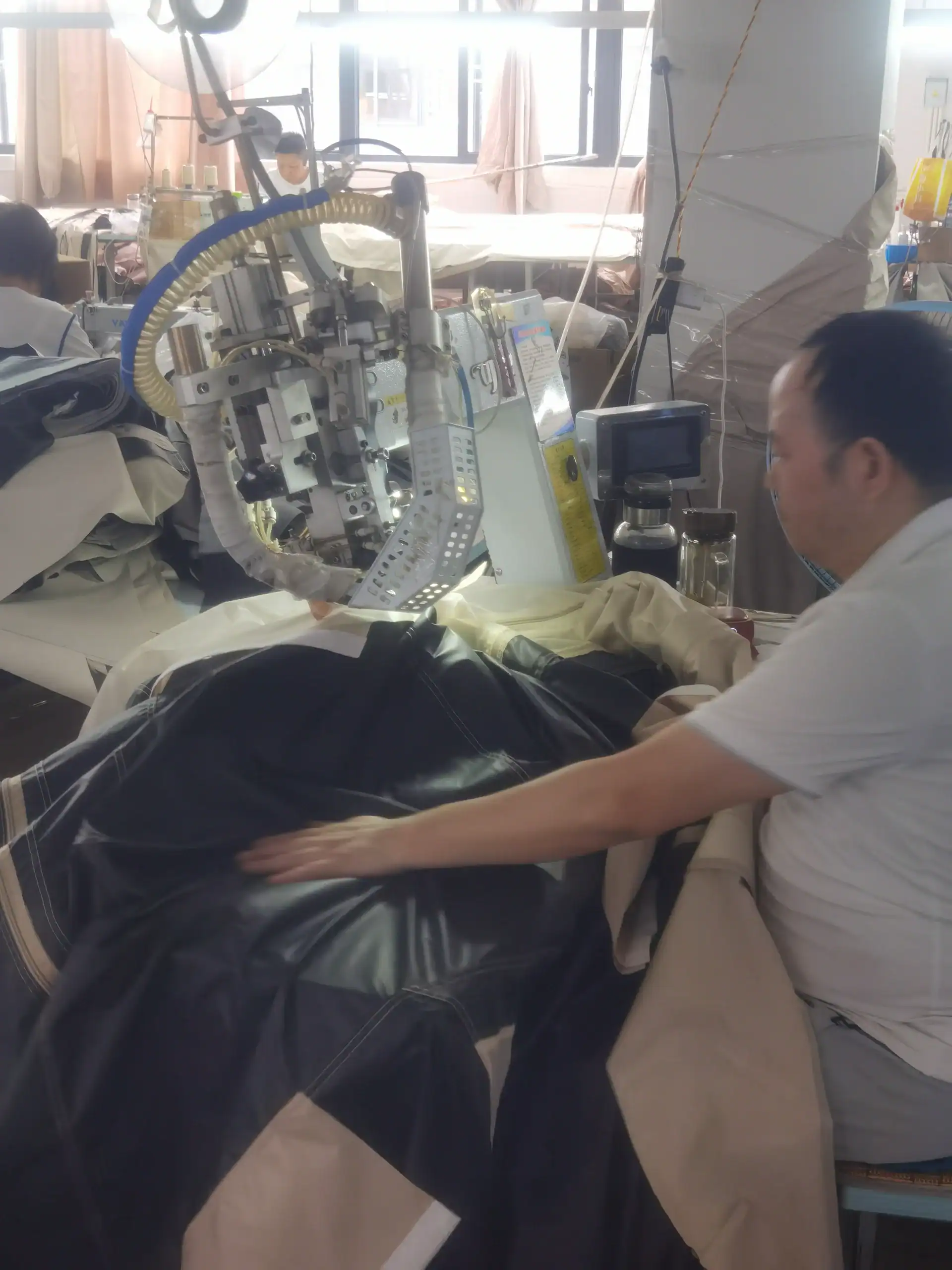Sourcing Camping Gear: 5 Mistakes That Kill Your Margin 25 Technician working on sewing machine assembling outdoor camping gear in a workshop with fabric and machinery in the background.