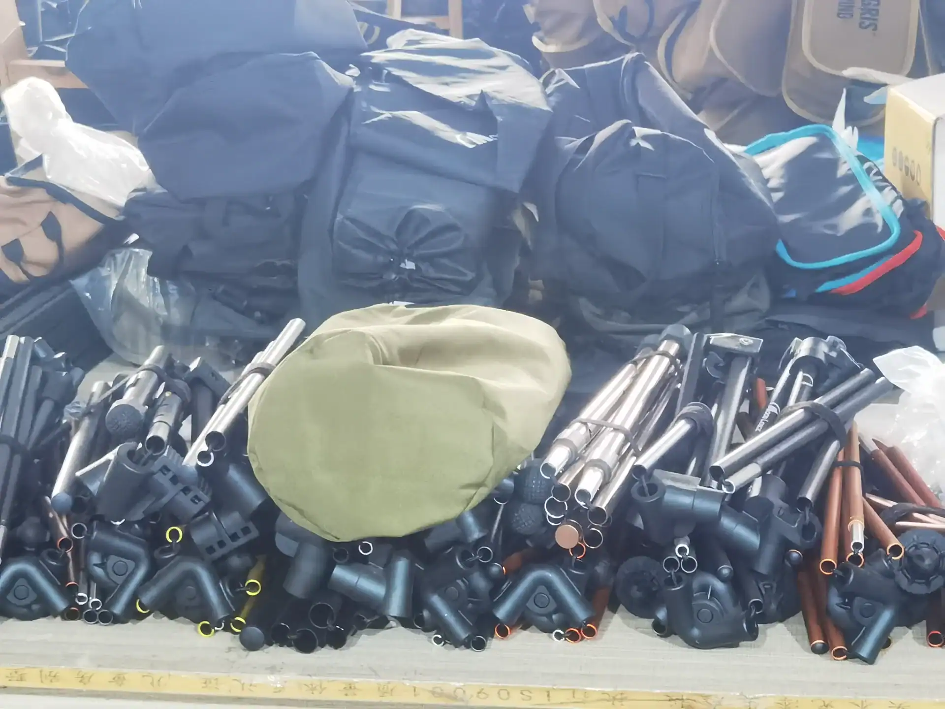 7 Sourcing Camping Gear Mistakes That Kill Profit Margins 135 Assorted camping gear parts including metal poles, plastic joints, and fabric components stacked on a surface.
