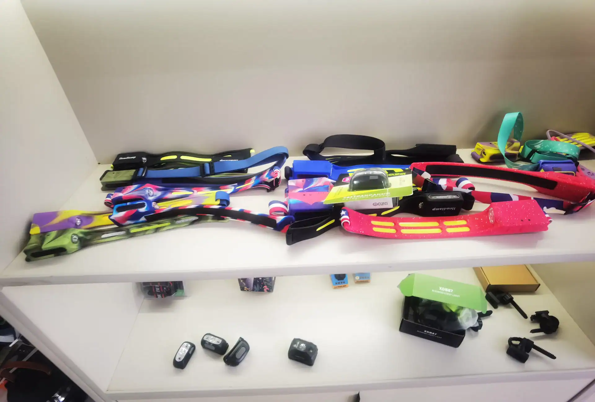 Folding Wagon Packaging Drop Test: The 60cm Export QC Rule 129 Brightly colored headlamps and accessories neatly displayed on white retail shelves, including adjustable straps and packaging.