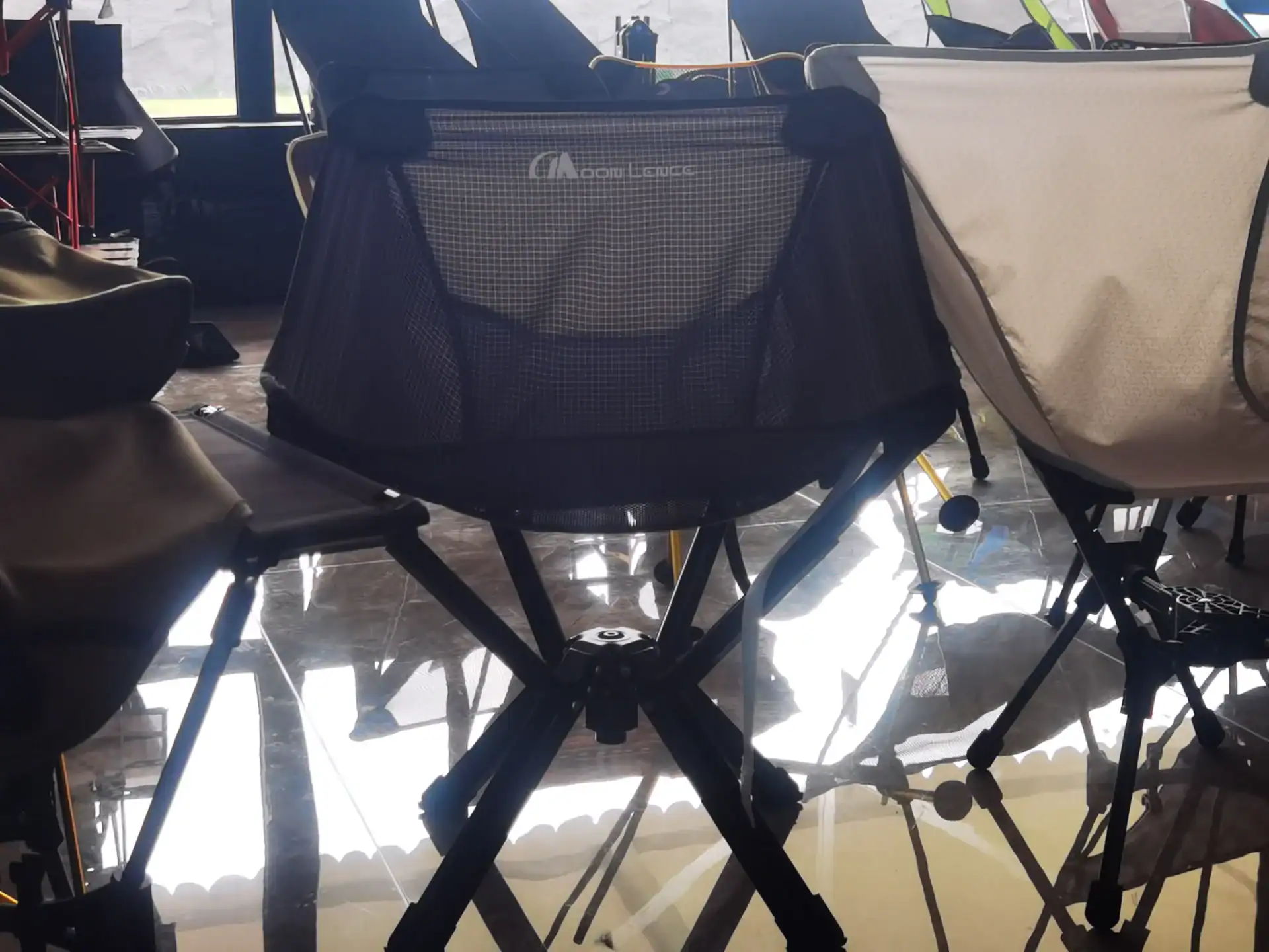 A variety of folding camping chairs displayed in a showroom setting, featuring modern and lightweight designs with sturdy frames.