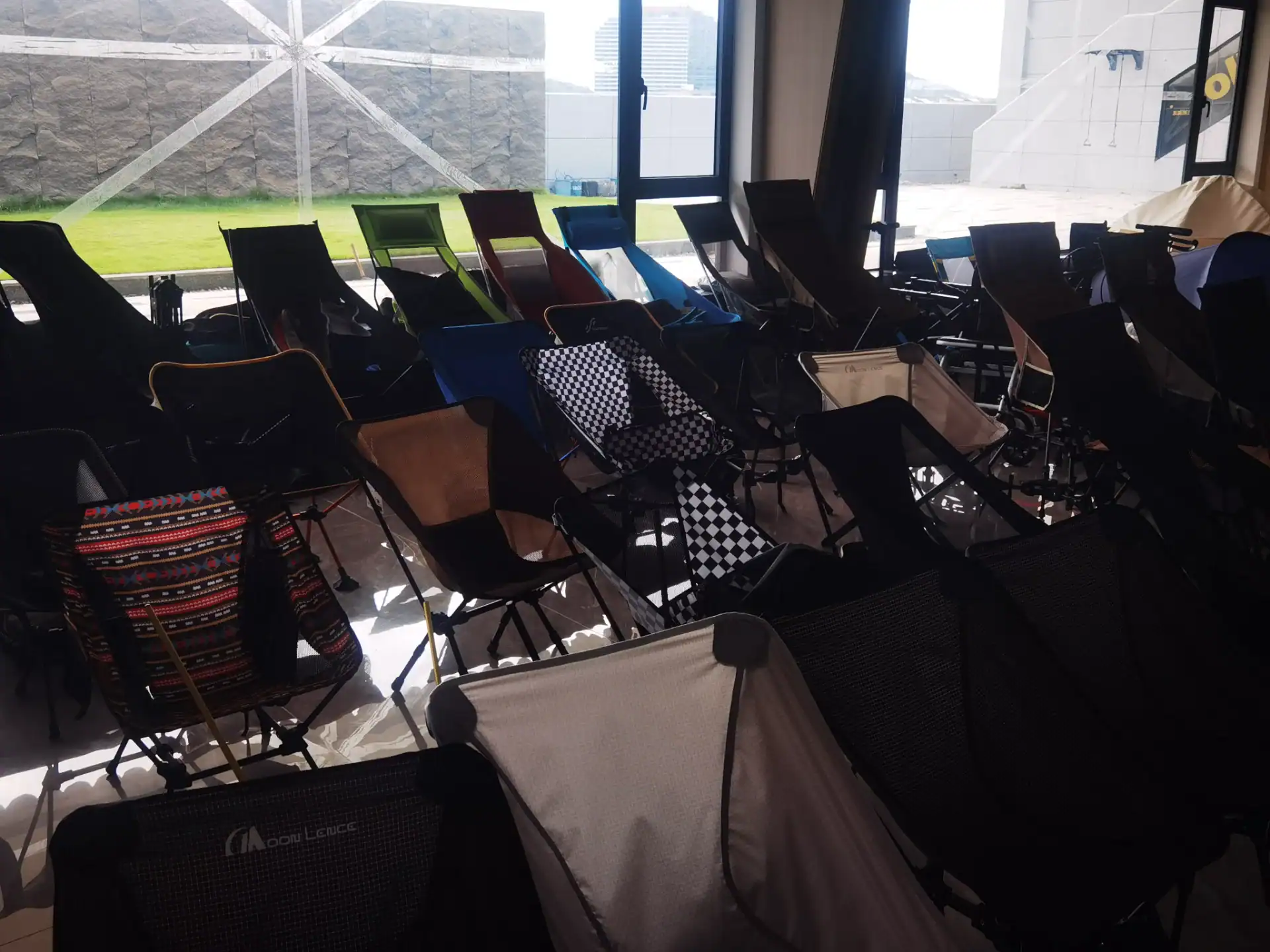 Folding Wagon Packaging Drop Test: The 60cm Export QC Rule 134 A diverse collection of portable and folding camping chairs displayed in an indoor setting, with natural light and an outdoor view.