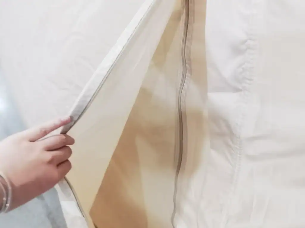 Hand pulling back white tent flap with visible zipper in close-up view, showcasing fabric texture and construction.