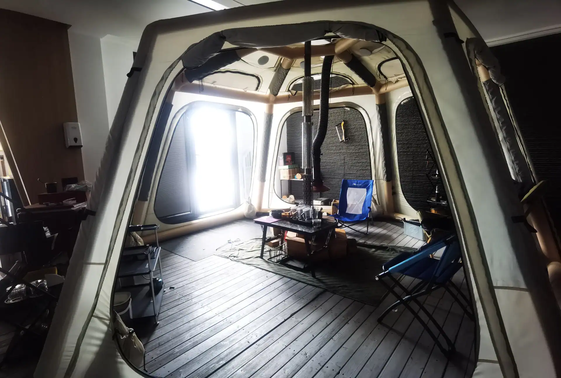 Drop-Stitch Air Mattress Buyers Guide: Cut Leak Returns 37 Spacious inflatable tent interior with camping setup, including a table, chairs, stove, and wooden flooring.