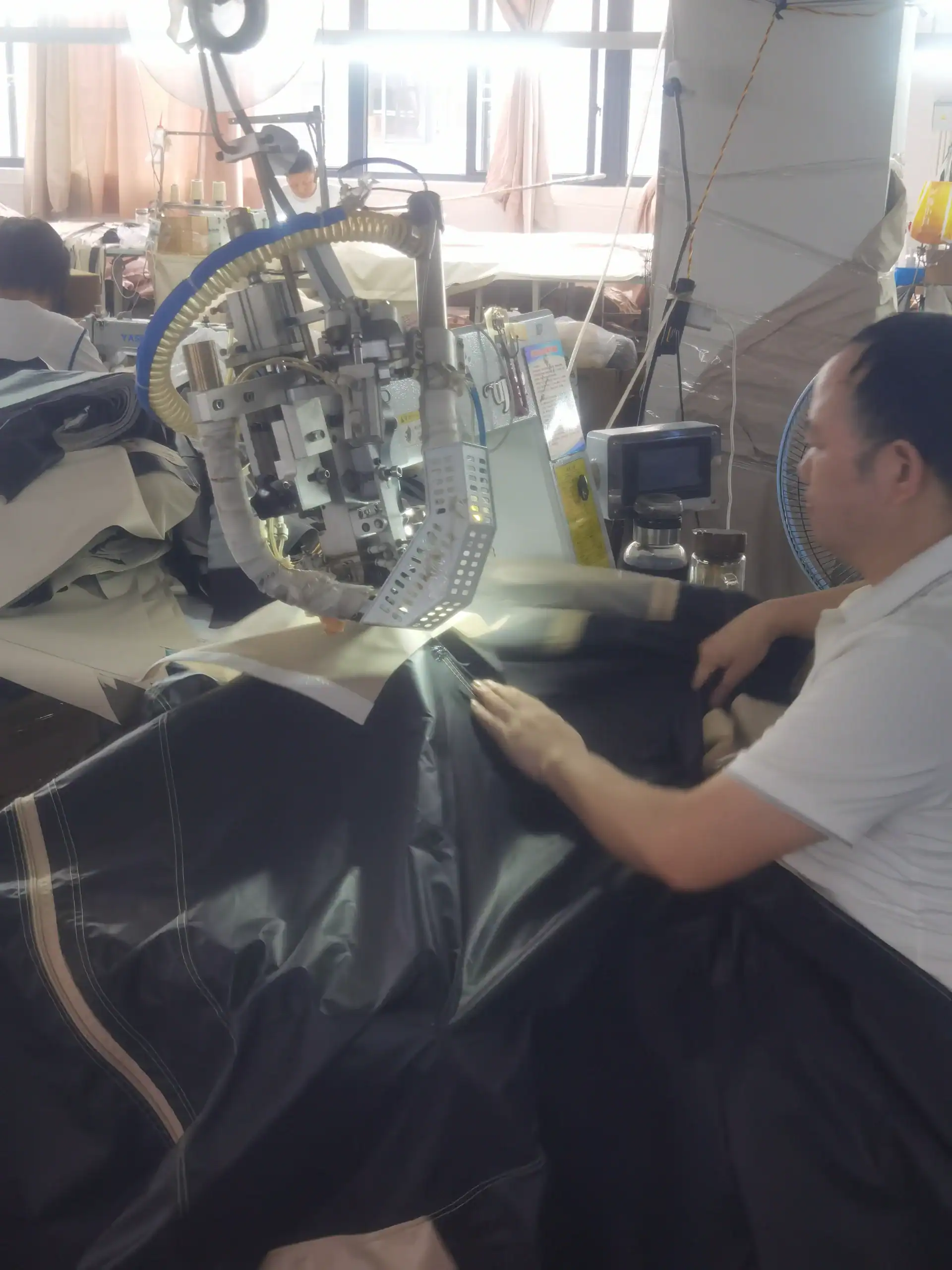Sourcing Camping Gear: 5 Mistakes That Kill Your Margin 26 A worker operates specialized sewing machinery to manufacture heavy-duty camping gear in a factory setting.